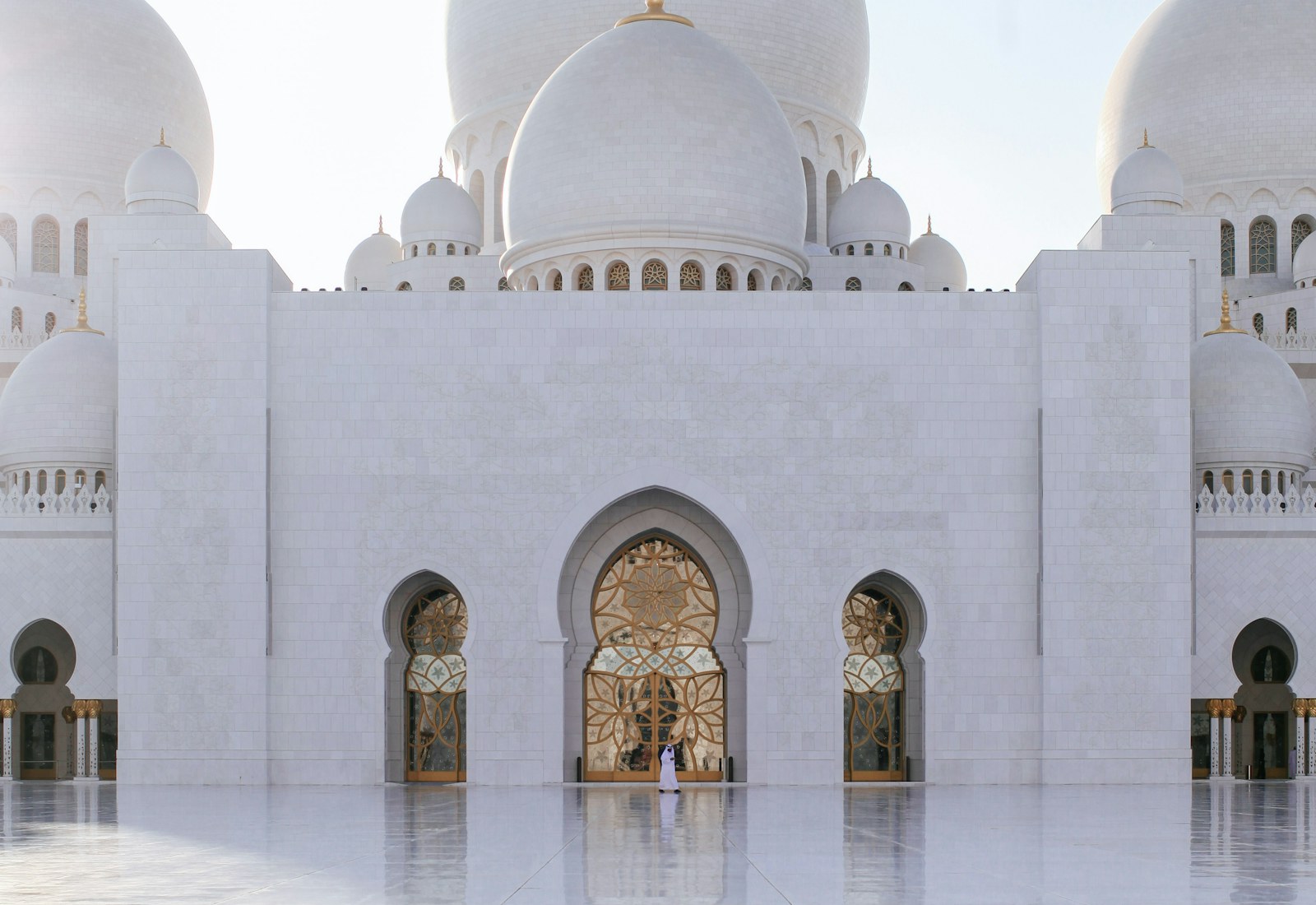 White mosque facade and domes in warm daylight